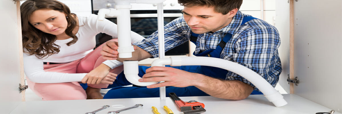 a woman looking at the plumber fixing the valve