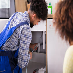 A plumber cleans the drain in the sink.